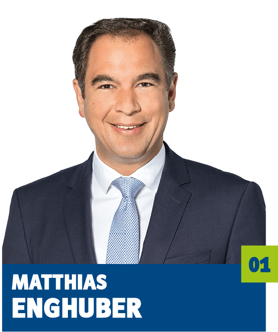 Professionelles Porträt von Matthias Enghuber vor dunklem Hintergrund. Er trägt ein weißes Hemd, eine hellblaue Krawatte und ein dunkles Sakko und lächelt freundlich in die Kamera. Der direkte Blick und das gepflegte Erscheinungsbild vermitteln Kompetenz, Seriosität und eine souveräne, vertrauensvolle Ausstrahlung und eignen sich ideal für die persönliche Vorstellung im beruflichen, politischen oder organisatorischen Kontext.