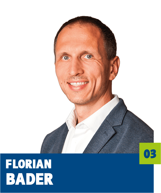 Professionelles Porträt von Florian Bader vor dunklem Hintergrund. Er trägt ein weißes Hemd und ein graues Sakko und blickt freundlich in die Kamera. Der direkte Blick und das gepflegte Erscheinungsbild vermitteln Kompetenz, Seriosität und eine ruhige, vertrauensvolle Ausstrahlung und eignen sich sehr gut für die persönliche Vorstellung im beruflichen oder organisatorischen Kontext.