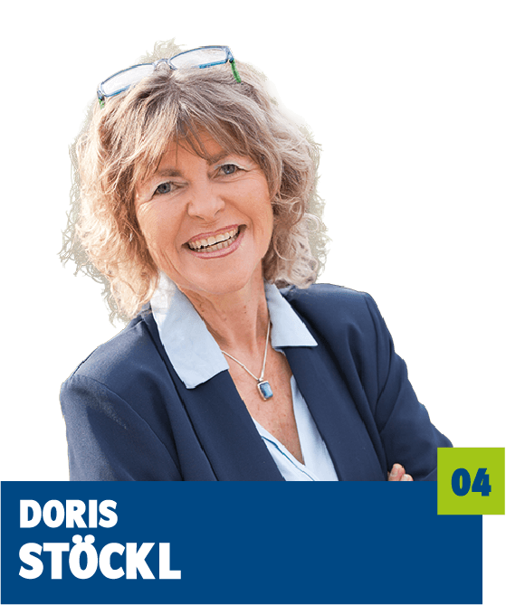 Professionelles Porträt von Doris Stöckl vor dunklem Hintergrund. Sie trägt eine helle Bluse, ein dunkles Sakko sowie eine Kette und hat eine Brille auf dem Kopf. Das offene Lächeln und die entspannte Haltung vermitteln Erfahrung, Offenheit und eine sympathische, vertrauensvolle Ausstrahlung und eignen sich sehr gut für die persönliche Vorstellung im beruflichen oder organisatorischen Kontext.