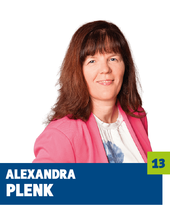 Professionelles Porträt von Alexandra Plenk vor dunklem Hintergrund. Sie trägt ein helles Oberteil und einen pinkfarbenen Blazer und blickt freundlich in die Kamera. Der offene Gesichtsausdruck und die lebendige Farbwahl vermitteln Kompetenz, Offenheit und eine sympathische, vertrauensvolle Ausstrahlung und eignen sich sehr gut für die persönliche Vorstellung im beruflichen oder organisatorischen Kontext.