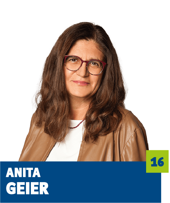 Professionelles Porträt von Anita Geier vor dunklem Hintergrund. Sie trägt eine helle Bluse, eine braune Jacke und eine Brille und blickt ruhig und freundlich in die Kamera. Die natürliche Farbwahl und der offene Gesichtsausdruck vermitteln Seriosität, Erfahrung und Vertrauen und eignen sich sehr gut für die persönliche Vorstellung im beruflichen oder organisatorischen Kontext.