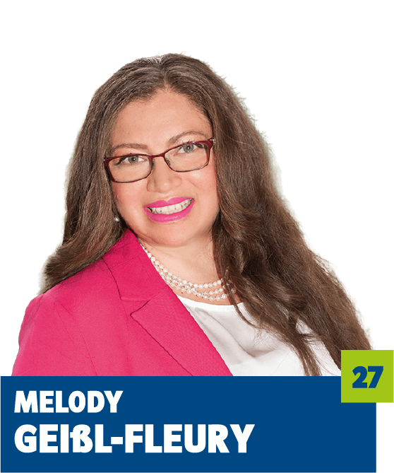 Professionelles Porträt von Melody Geißl-Fleury vor dunklem Hintergrund. Sie trägt einen pinkfarbenen Blazer über einer weißen Bluse, dazu eine Perlenkette und eine Brille. Das freundliche Lächeln und der direkte Blick in die Kamera vermitteln Kompetenz, Offenheit und eine selbstbewusste, nahbare Ausstrahlung – ideal für die persönliche Vorstellung im beruflichen oder organisatorischen Kontext.
