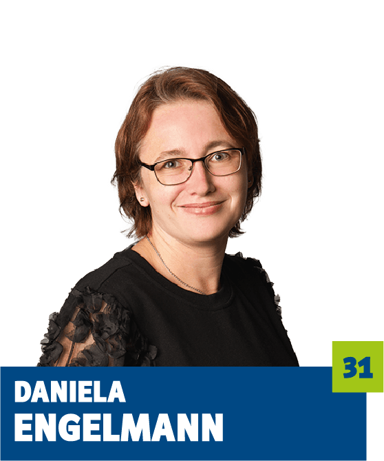 Professionelles Porträt von Daniela Engelmann vor dunklem Hintergrund. Sie trägt eine schwarze Bluse mit transparenten Ärmeldetails und eine Brille, die ihr ein kompetentes und sympathisches Auftreten verleiht. Der freundliche Blick in die Kamera unterstreicht eine ruhige, vertrauensvolle Ausstrahlung und eignet sich ideal für die persönliche Vorstellung im beruflichen oder organisatorischen Kontext.