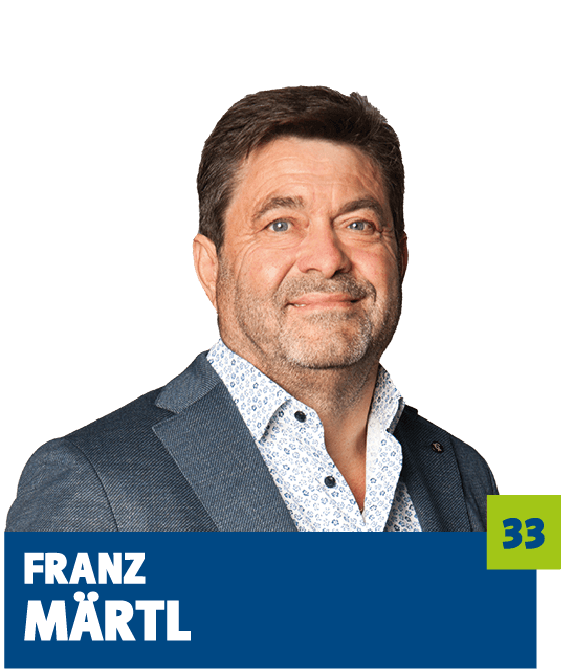 Professionelles Porträt von Franz Märtl vor dunklem Hintergrund. Er trägt ein hell gemustertes Hemd und ein graues Sakko und blickt freundlich in die Kamera. Das Bild wirkt seriös und persönlich zugleich und eignet sich für die Vorstellung einer Person im unternehmerischen oder politischen Kontext.